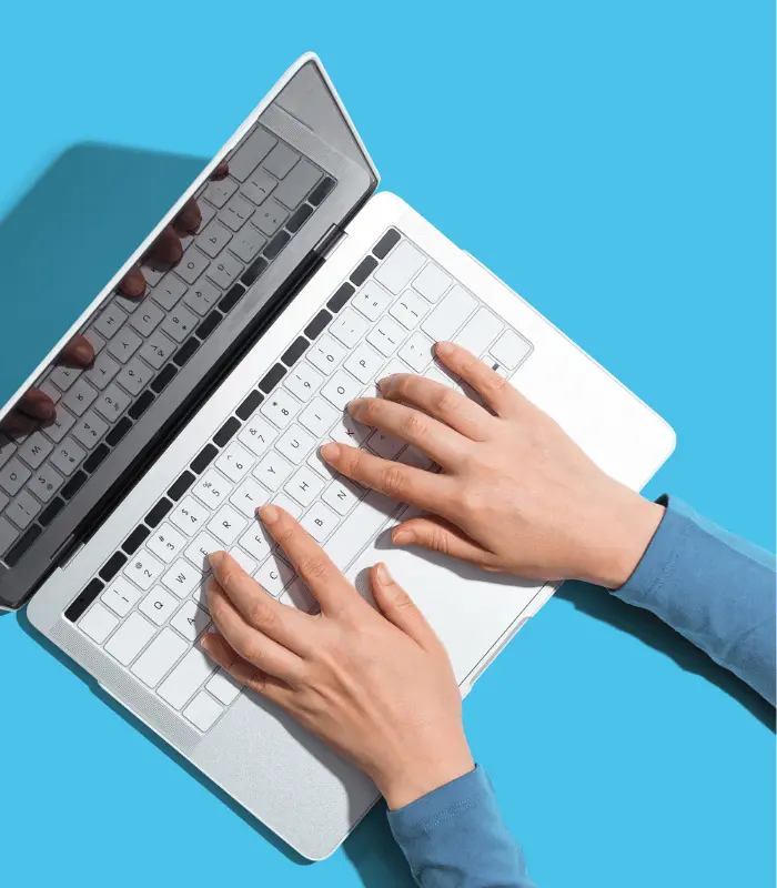 Overhead view of someone at a laptop, weighing up business websites before deciding who to contact